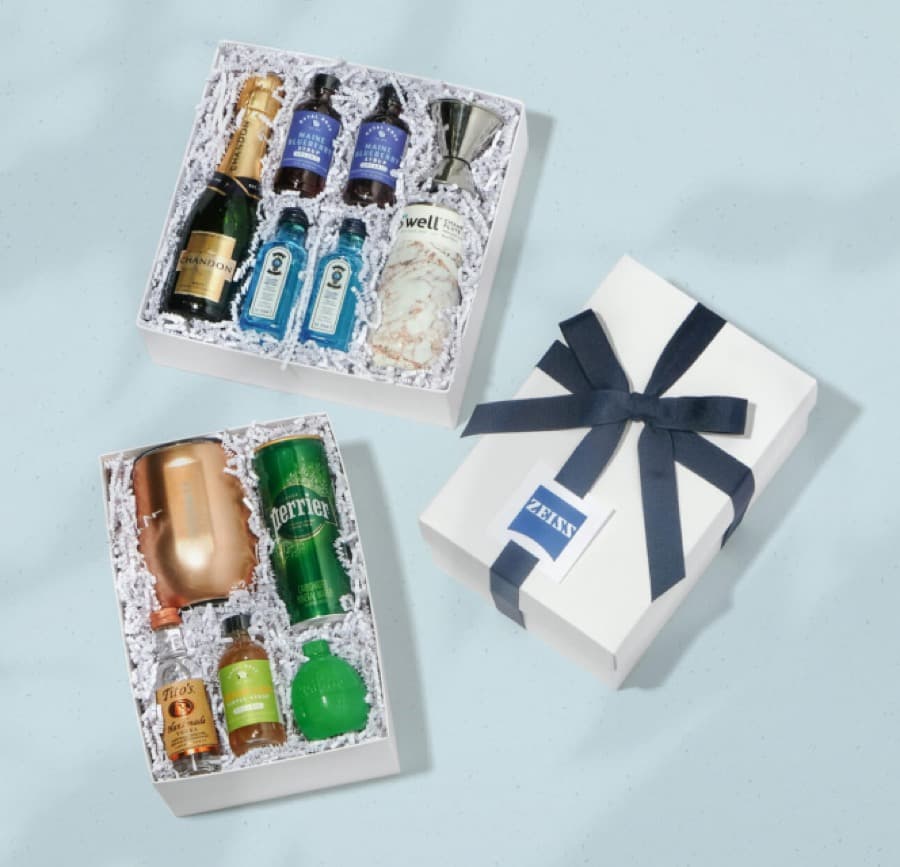 Two cocktail kits next to a gift box with a branded tag and navy ribbon
