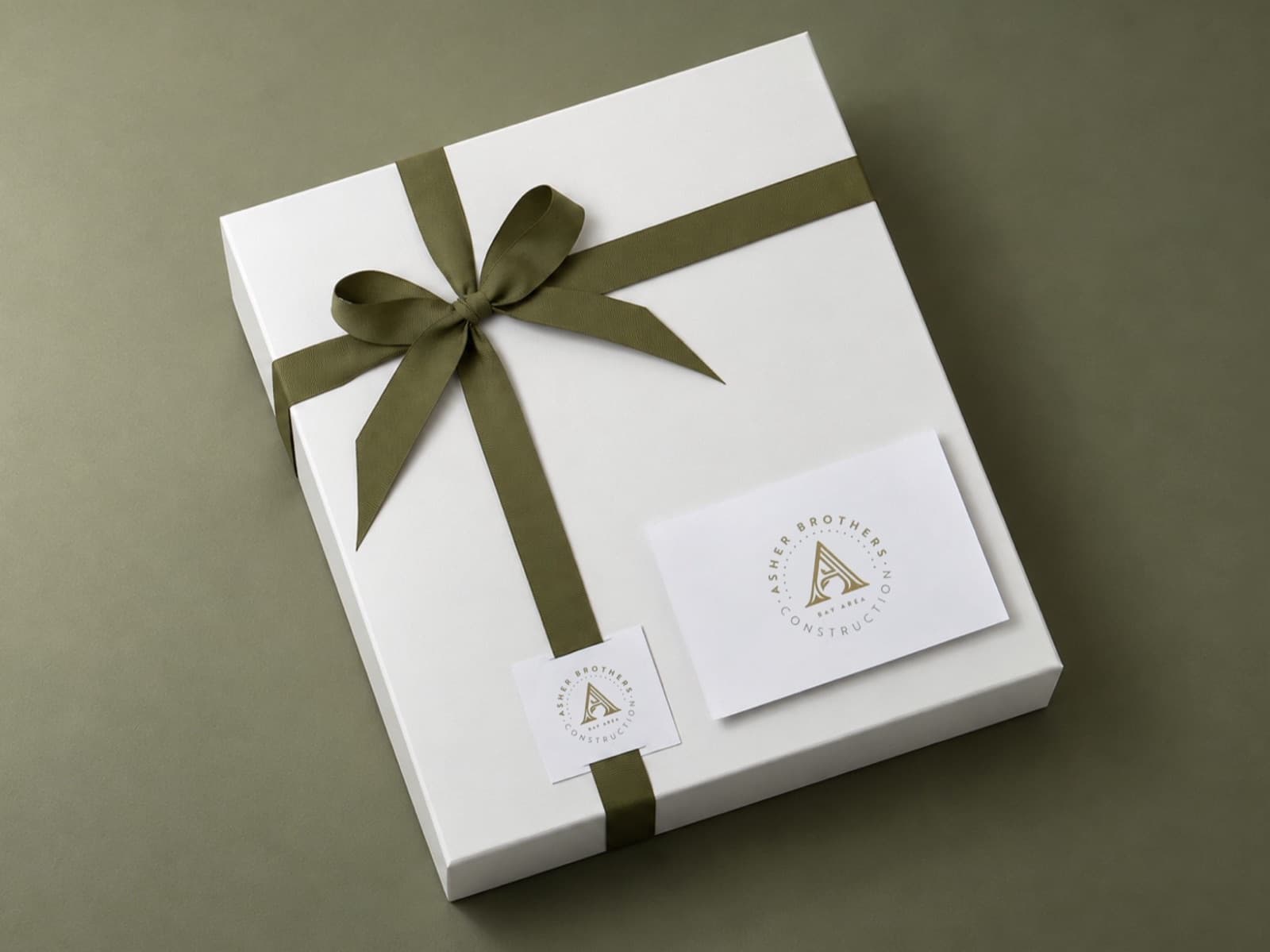 A gift box tied with an olive ribbon, with a logo tag and a logo card