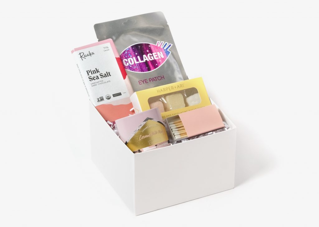 gift box of exfoliation sugar cubes, collagen eye mask, pink sea salt chocolate bar, coconut milk mango tin candle, box of matches
