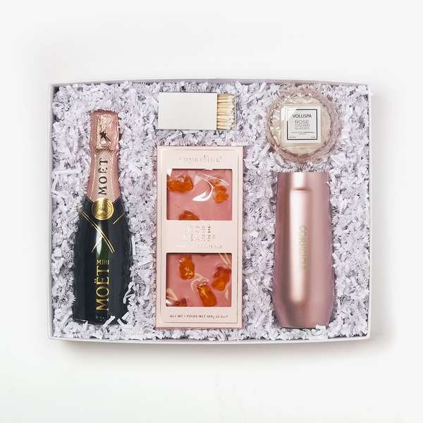 gift box of mini bottle of moet rose, rose gummy bear chocolate bar, stemless rose color champagne flute, small round candle and box of matches 
